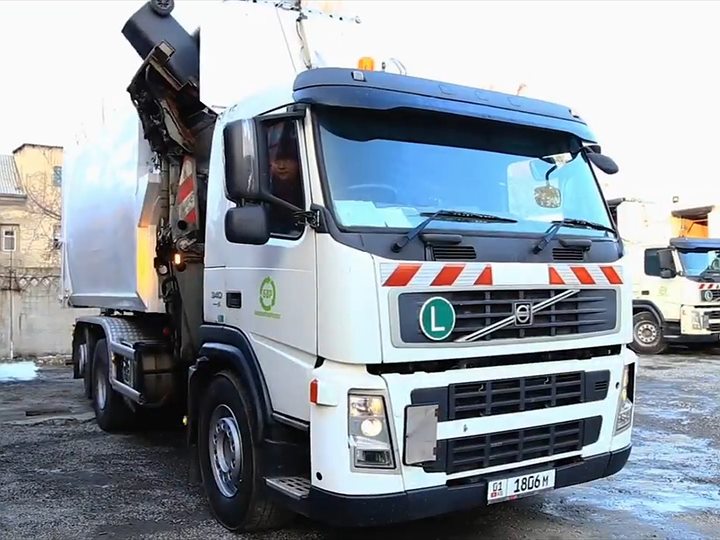 Мусоровоз Volvo БишкекВторРесурс поднимает контейнер боковым манипулятором